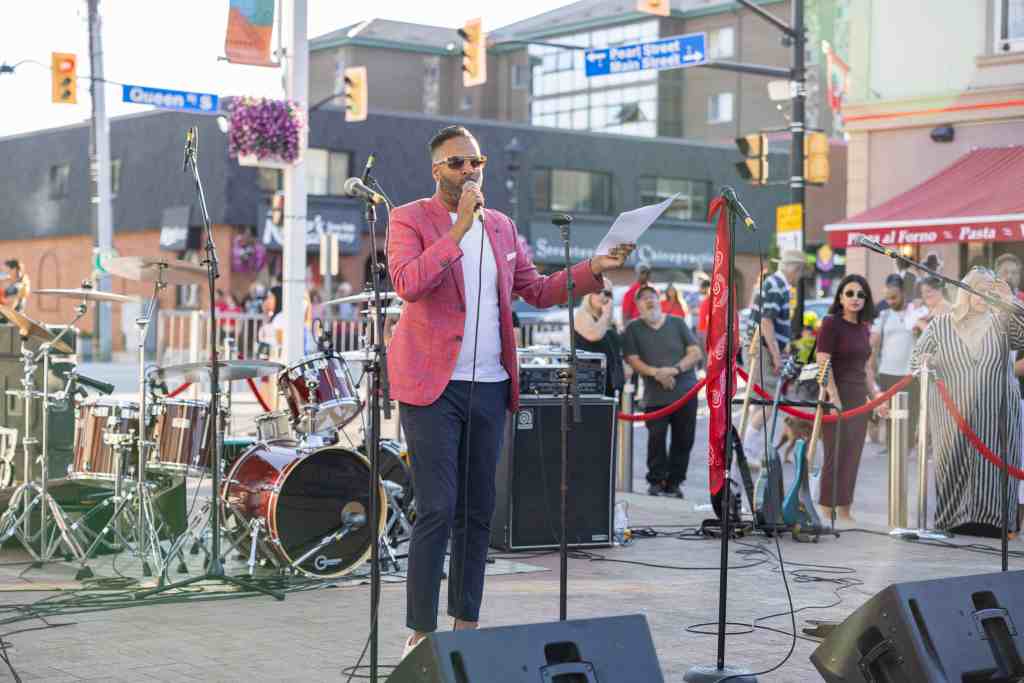 Event speaker holding a microphone on an outdoor stage in Mississauga