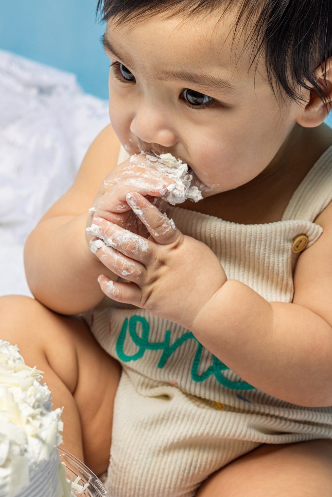 Baby eating birthday cake during a first birthday cake smash session in Mississauga