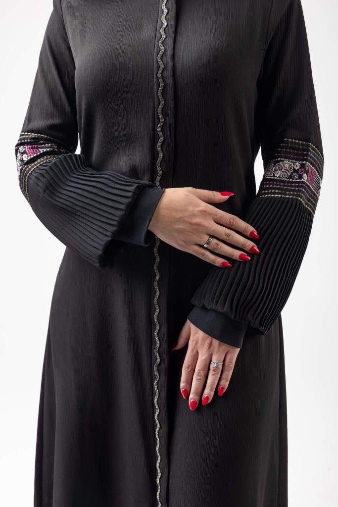 Close-up fashion photograph highlighting the details and sleeves of a black dress