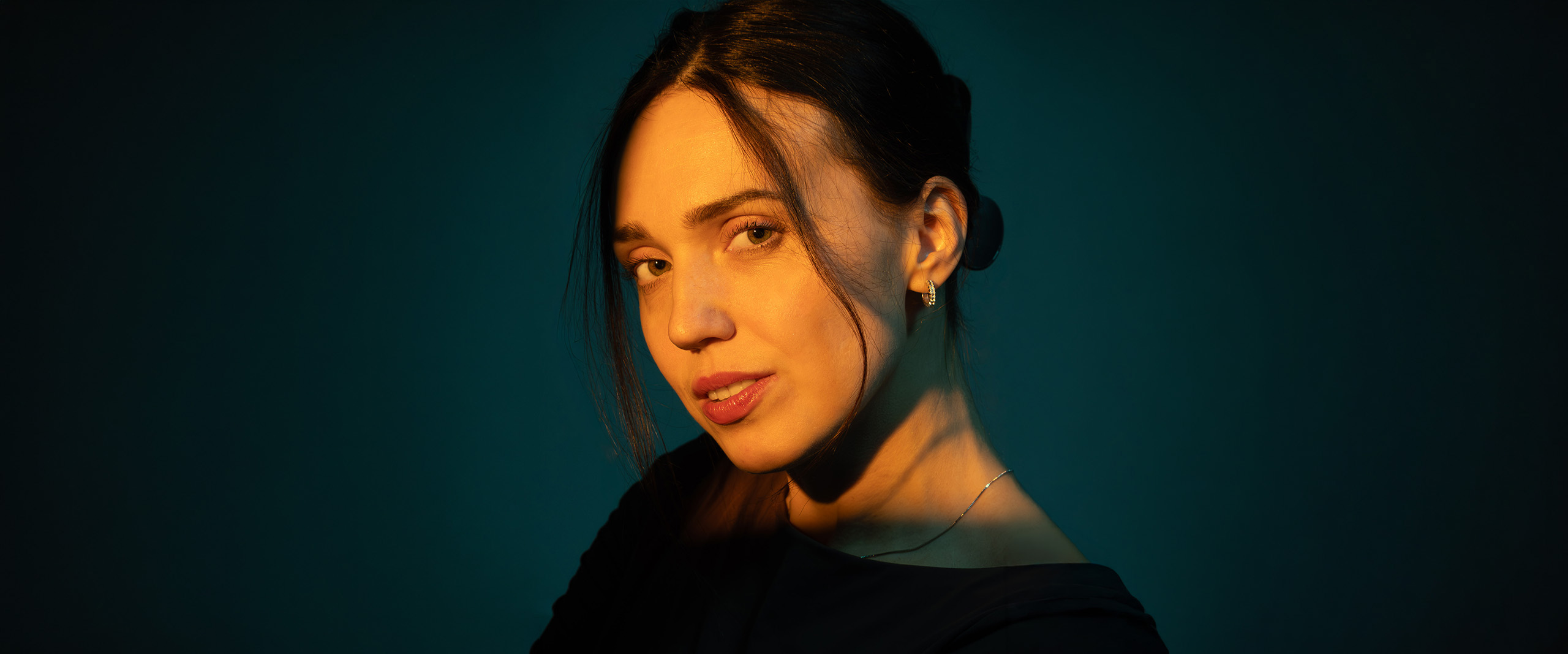 Creative studio portrait of a woman with warm cinematic lighting against a teal background